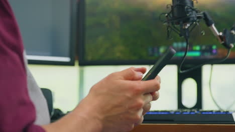 close up of male vlogger scrolling through mobile phone before live stream- shot in slow motion