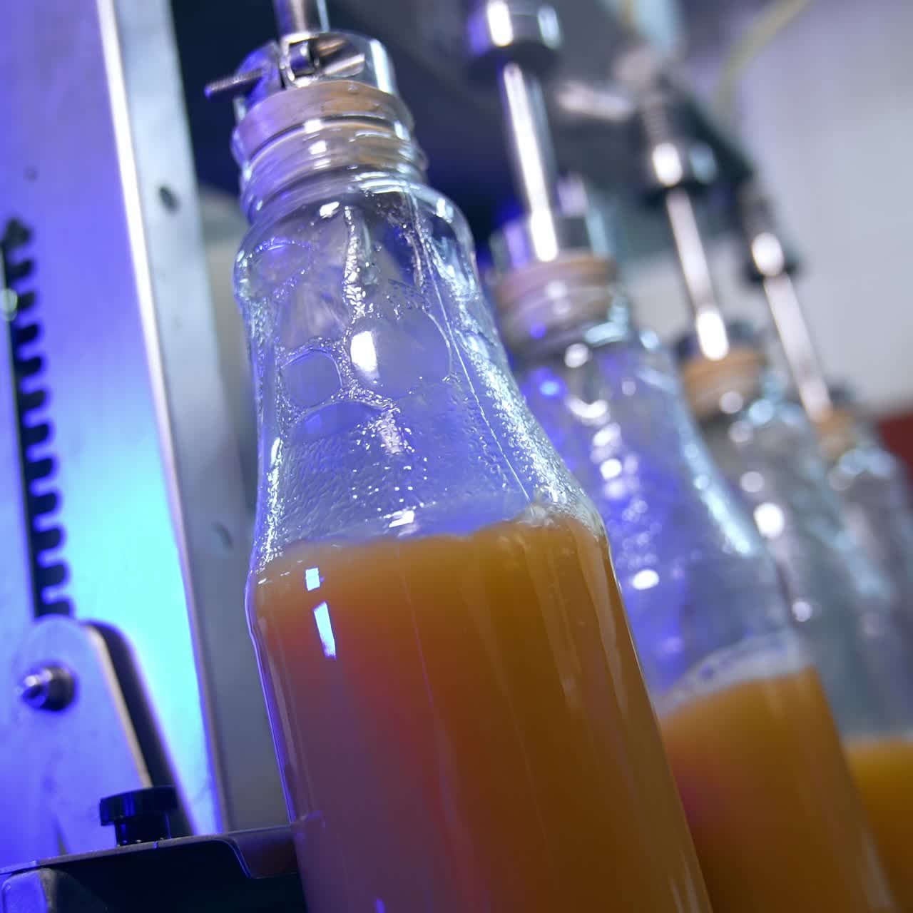 Apple juice being poured into the glass bottles. Close up. Automated line at modern food factory. Blurred background
