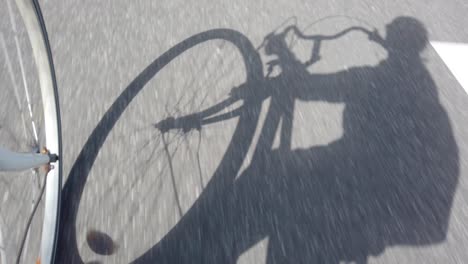 shadow of cyclist biking on asphalt road, slow motion