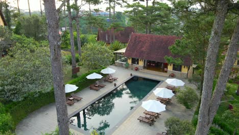 un dron aéreo que vuela sobre una hermosa piscina bajo el sol revela el paisaje del resort en la colina_dalat vietnam_4k 24fps
