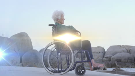 animación de la luz moviéndose sobre una mujer caucásica mayor sonriente en silla de ruedas en la playa mirando al mar