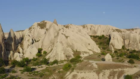 Drone-flying-over-green-farmland-valley-fields-between-rock-formations-Cappadocia-turkey