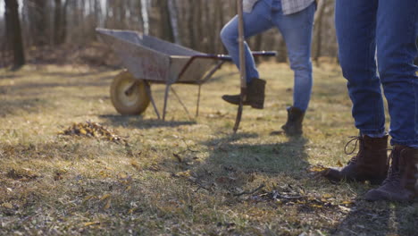 close-up view of a woman is removing weeds in the countryside. on the background her partner are looking her