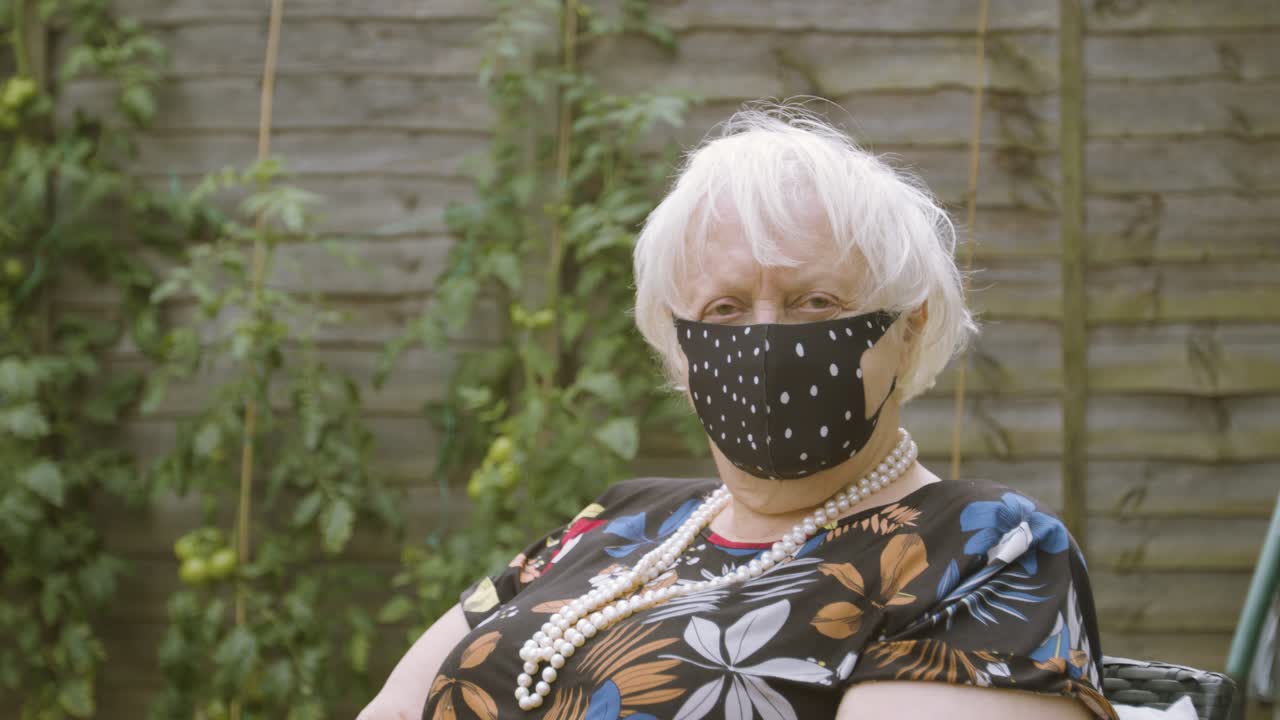 폴카 도트 마스크를 쓴 노인 여성이 카메라를 보며 웃고 있다