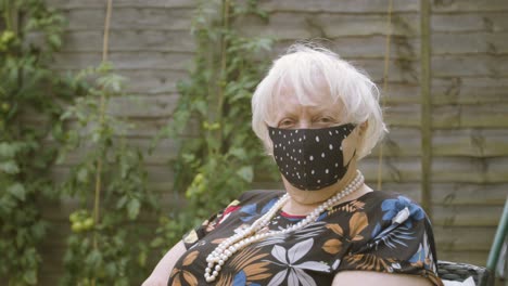 Elderly-Woman-wearing-a-polka-dot-face-mask-looking-at-the-camera-smiling