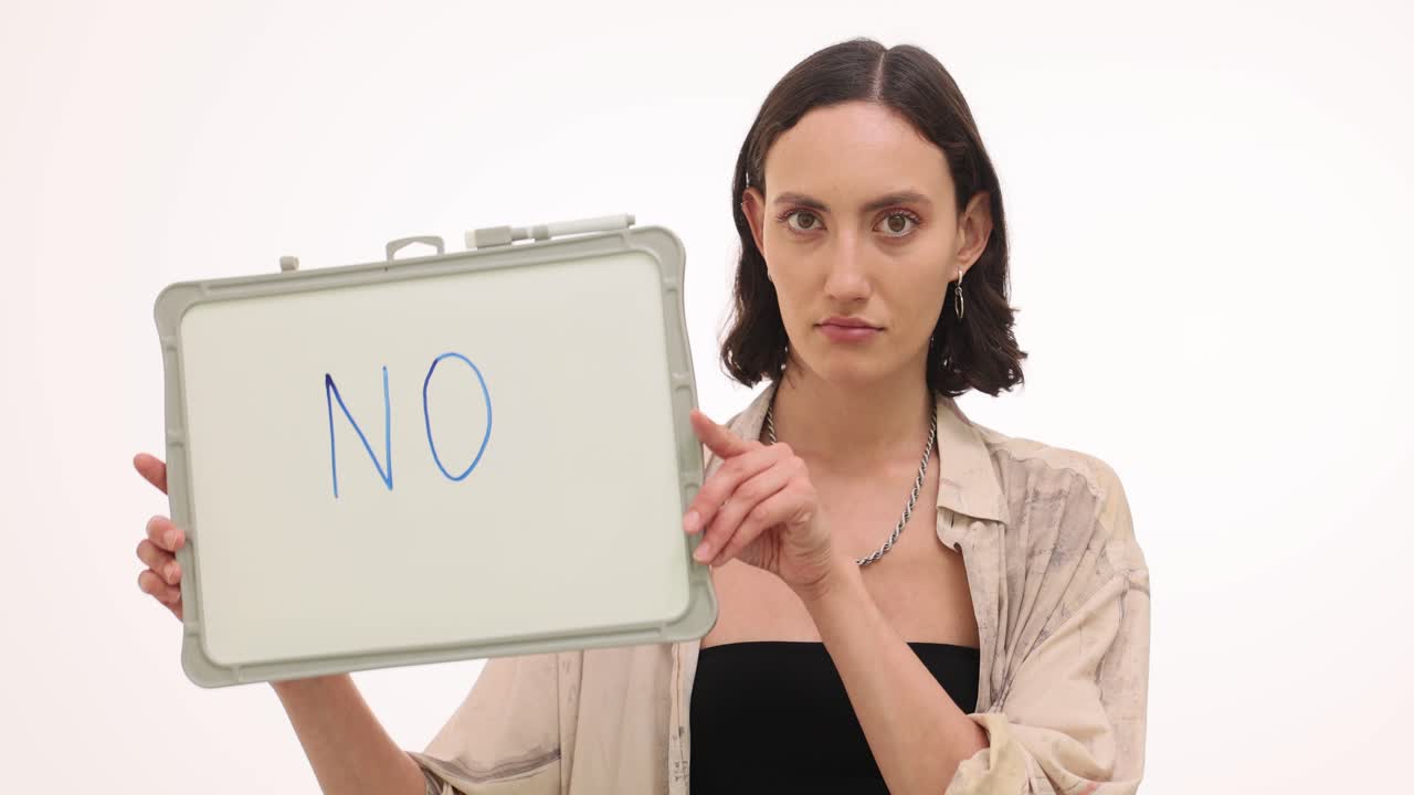 Woman holding a whiteboard with 'NO' message