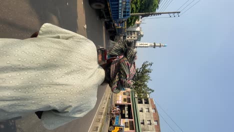 Dhaka,-Bangladesh,-:Vertical-shot-of-man-driving-a-trishaw-in-the-chaotic-traffic-of-Dhaka-from-the-perspective-of-the-passenger-with-the-driver-in-the-foreground,-Bangladesh