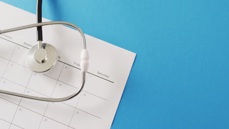 video of stethoscope on calendar, on blue background with copy space