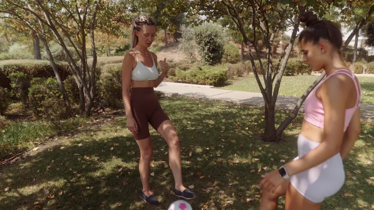 Two women playing soccer in the park