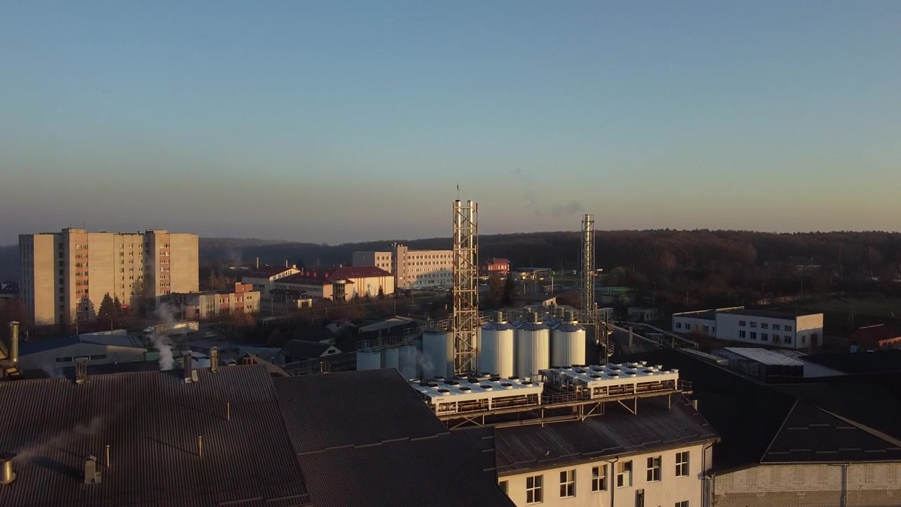 Vista aerea di un drone che sorvola il birrificio, diverse file di serbatoi