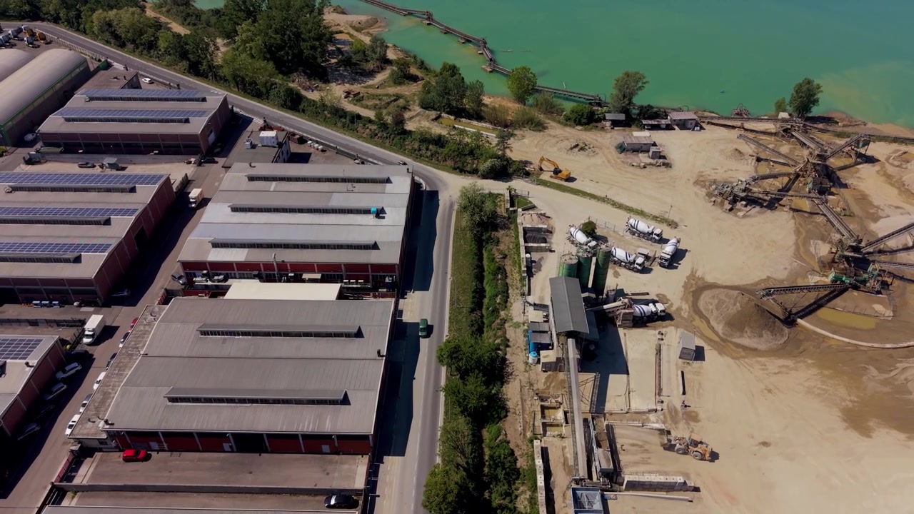 Aerial view of full production cycle in gravel quarry in Italy. Extraction, sorting and concrete production with heavy industrial machinery and transport operations.