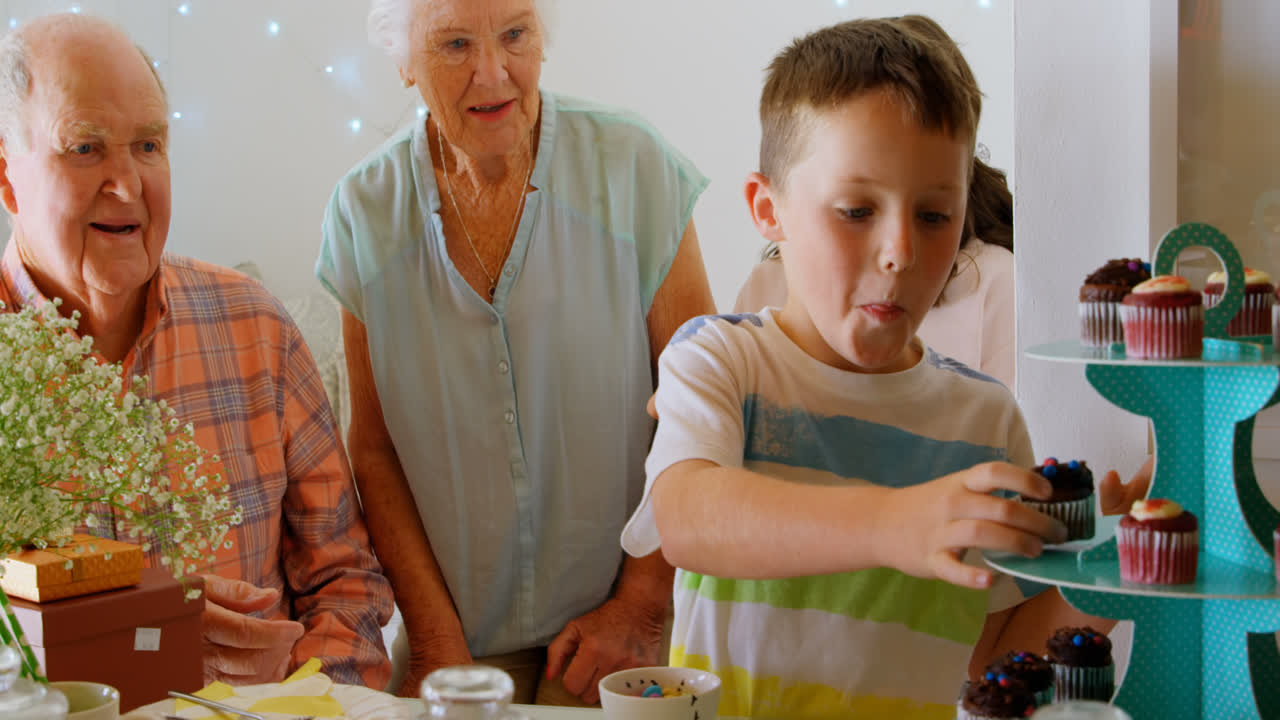 niño caucásico le da cupcake a su abuelo en un hogar cómodo 4k