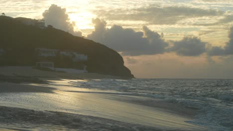 Wunderschöner-Sonnenuntergang-Am-Strand-Von-Baie-Rouge-Mit-Wolken-Am-Himmel-Und-Wellen,-Die-Ans-Ufer-Schlagen