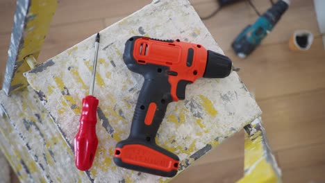 cordless drill and screwdriver on a paint-splattered stepladder