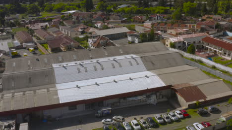 aerial shot captured with a drone showing a landscape composed of homes, a factory, mountains in the background, and large green areas.
