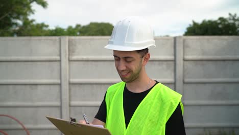 a manager donning a white hard hat gives their approval to the information recorded on the clipboard - medium close up