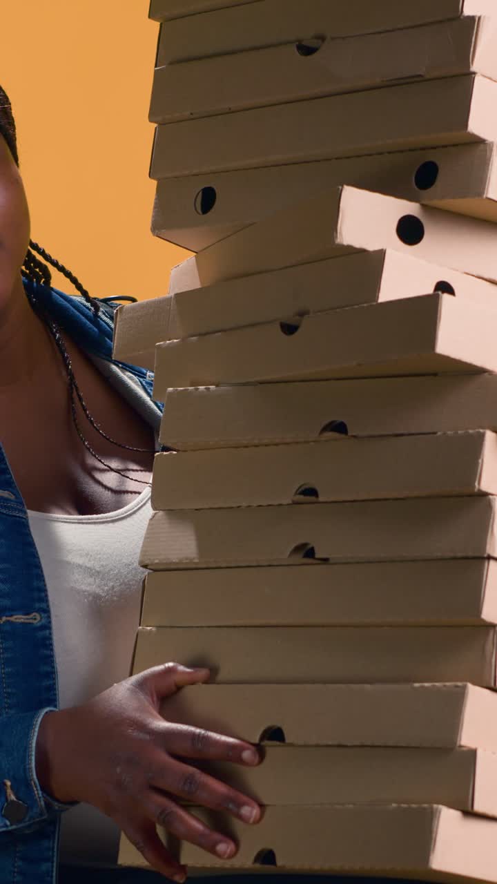 Seorang wanita membawa setumpuk kotak pizza untuk pengiriman