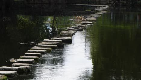 Tilt-down-along-winding-stone-bridge-of-Poldras-de-Chaves,-Vila-Real-Portugal