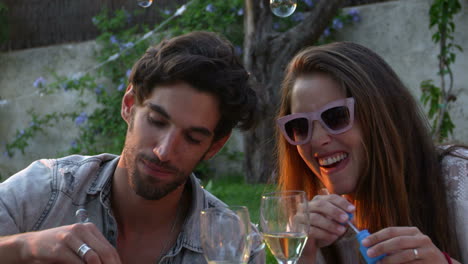 couple blowing bubbles during picnic in garden