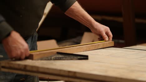 building a boat, a carpenter at work takes precise measurements of wood