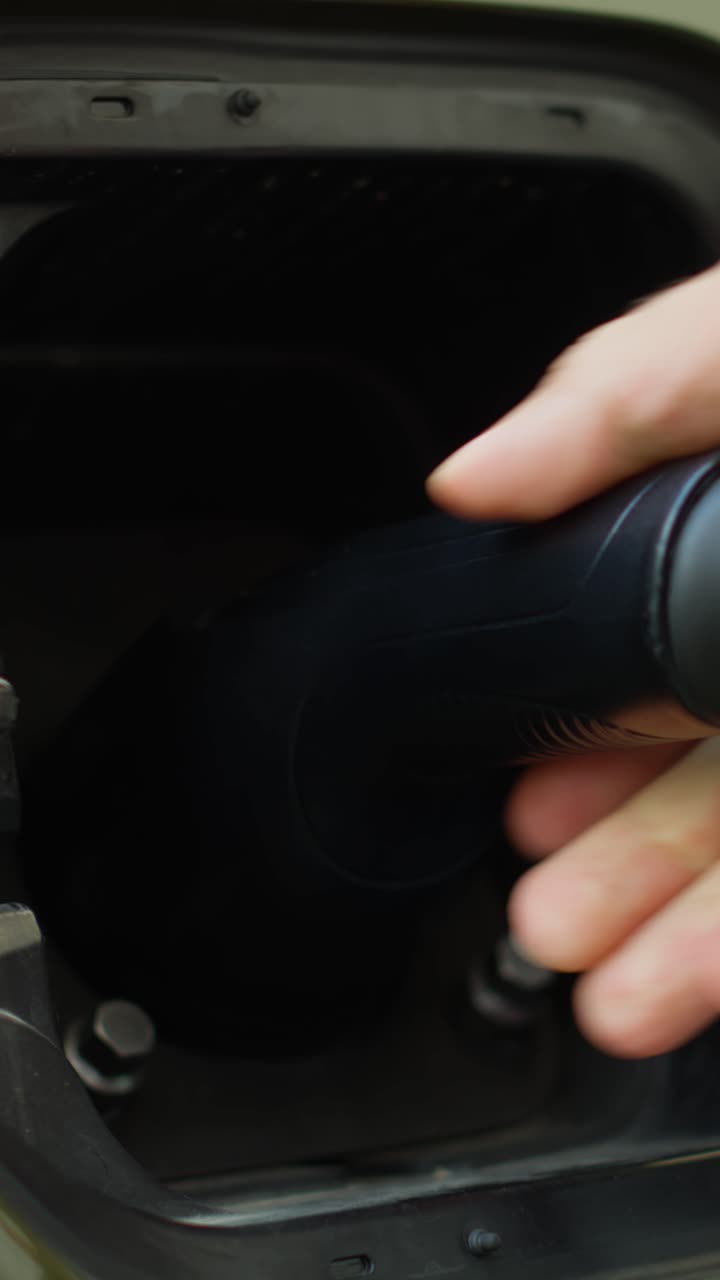 Vertical video Extreme close up of driver opening charging port flap, plugging electric car