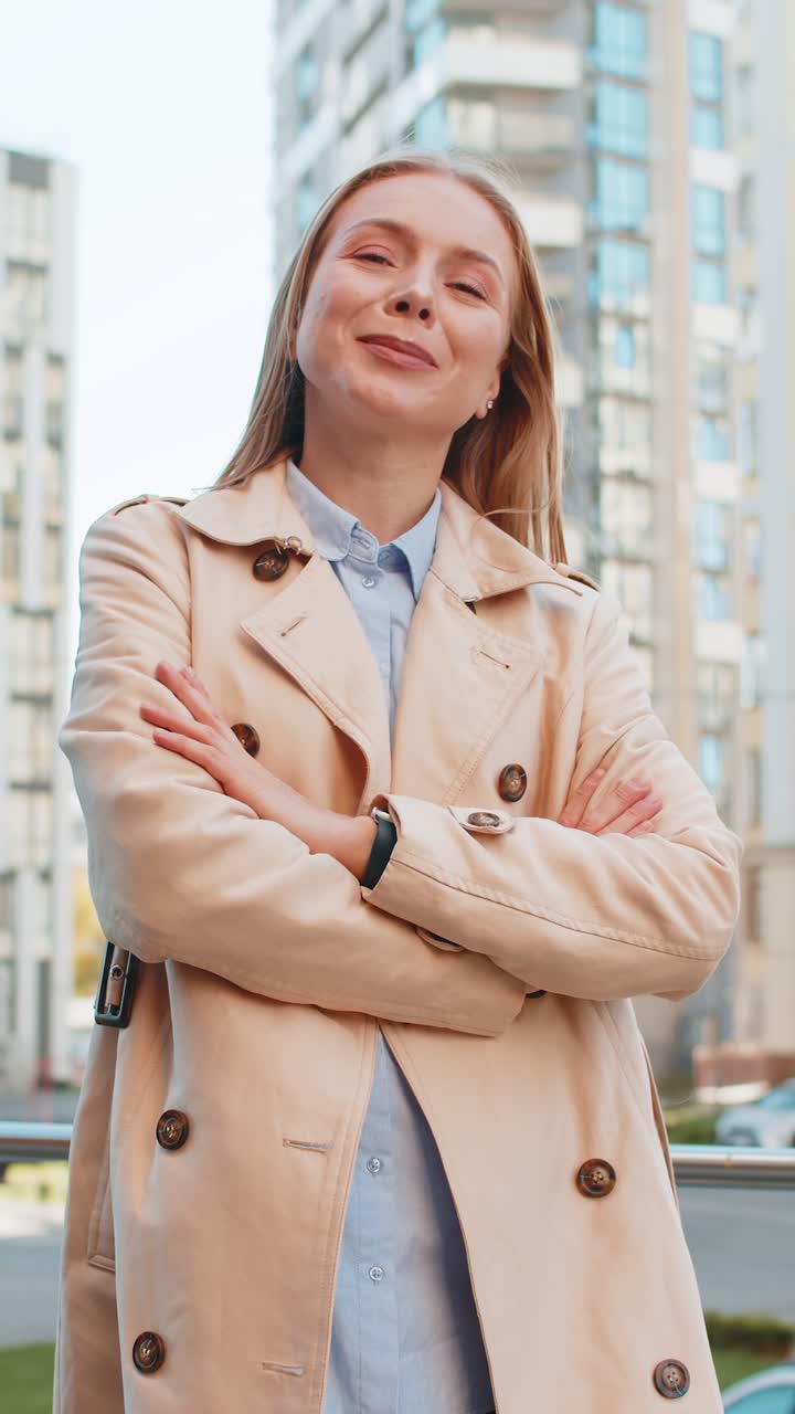 retrato de una mujer madura rubia feliz girándose y mirando a la cámara con los brazos cruzados en la calle