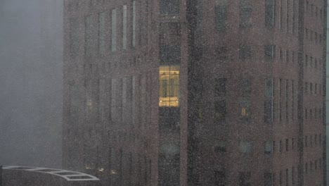 tight view of old building exterior with white out snowy blizzard blowing in slow motion from the side with single light on