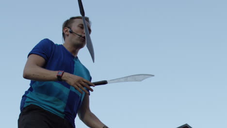 slow motion juggler with swords in city busker