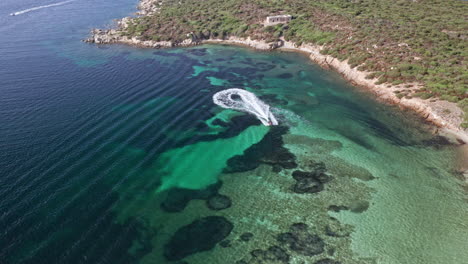 A-boat-creating-a-whirlpool-near-the-stunning-coastline-of-sardinia,-aerial-view