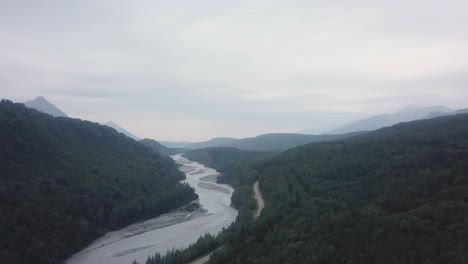 Aerial-view,-drone-flight-along-the-Glenn-Highway-and-the-Matanuska-River-in-the-Chugach-Mountain-Range-of-central-Alaska-on-a-cloudy-summer-day