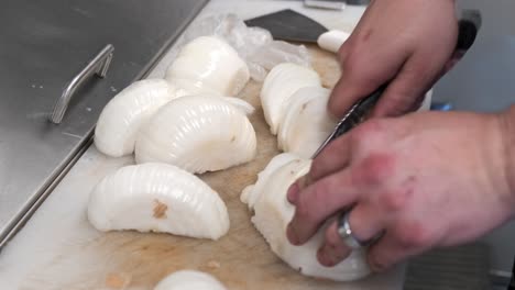 a close up shot of half onions being chopped into slices by hand