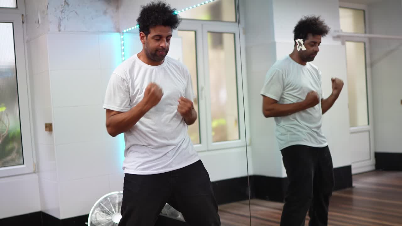 Mand, der danser i et dansestudie med spejl og neonlys