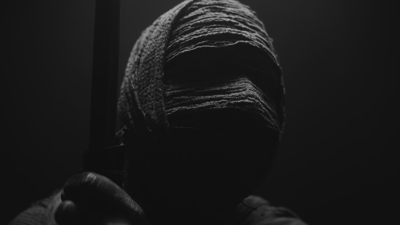 A mummified woman against the dark background pose with the walking staff