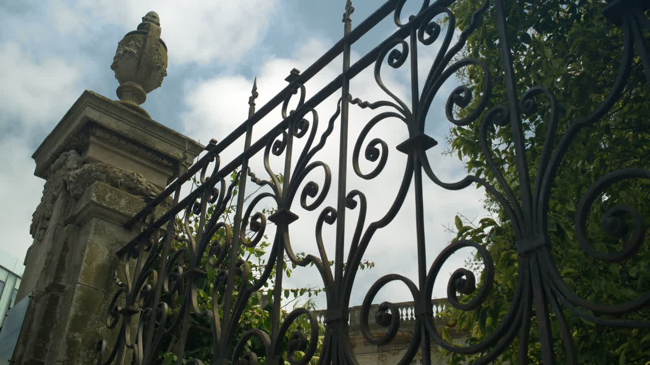 Close view of decorative wrought iron gate and stone pillar