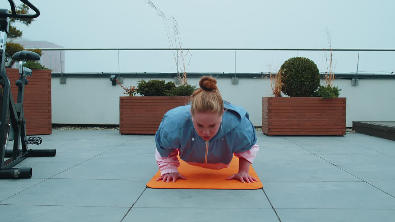 Athletic woman do pushups exercises cross fitness bodybuilding training routine on house rooftop