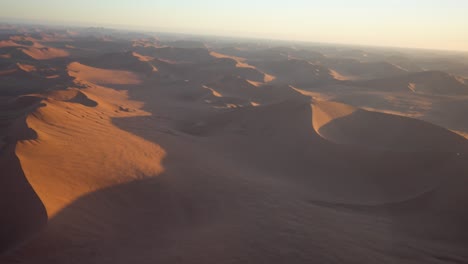 amplia toma épica de sossuvlei namibio durante la puesta de sol con bonitas sombras en la arena naranja