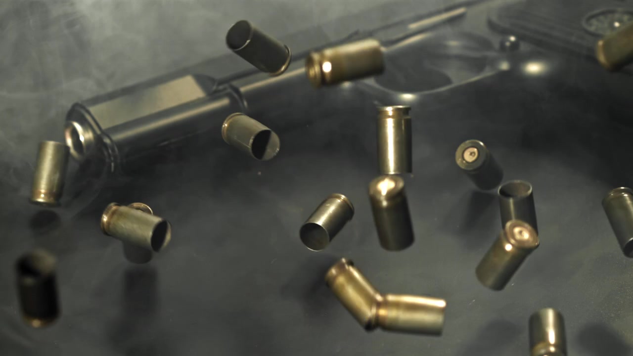 Bullet Casings Falling in Slow Motion Around a Handgun in Smoke