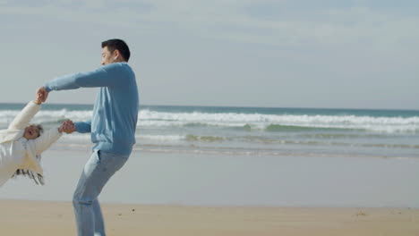 japanese dad spinning his little daughter around at seashore on sunny day