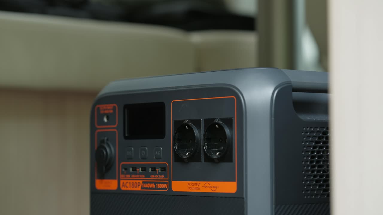 Hand puts electric plug into socket of power booster for electric while camping, off grid living in camper
