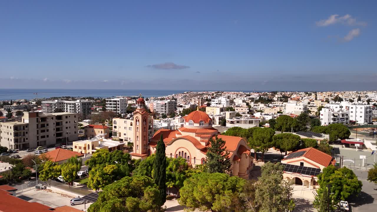 Stunning aerial panorama of a coastal city, showcasing unique buildings, lush greenery, and the distant sea under a bright blue sky. A vibrant urban landscape awaits exploration