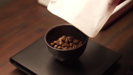 pour coffee beans in ceramic cup to get precise weight on electronic scale