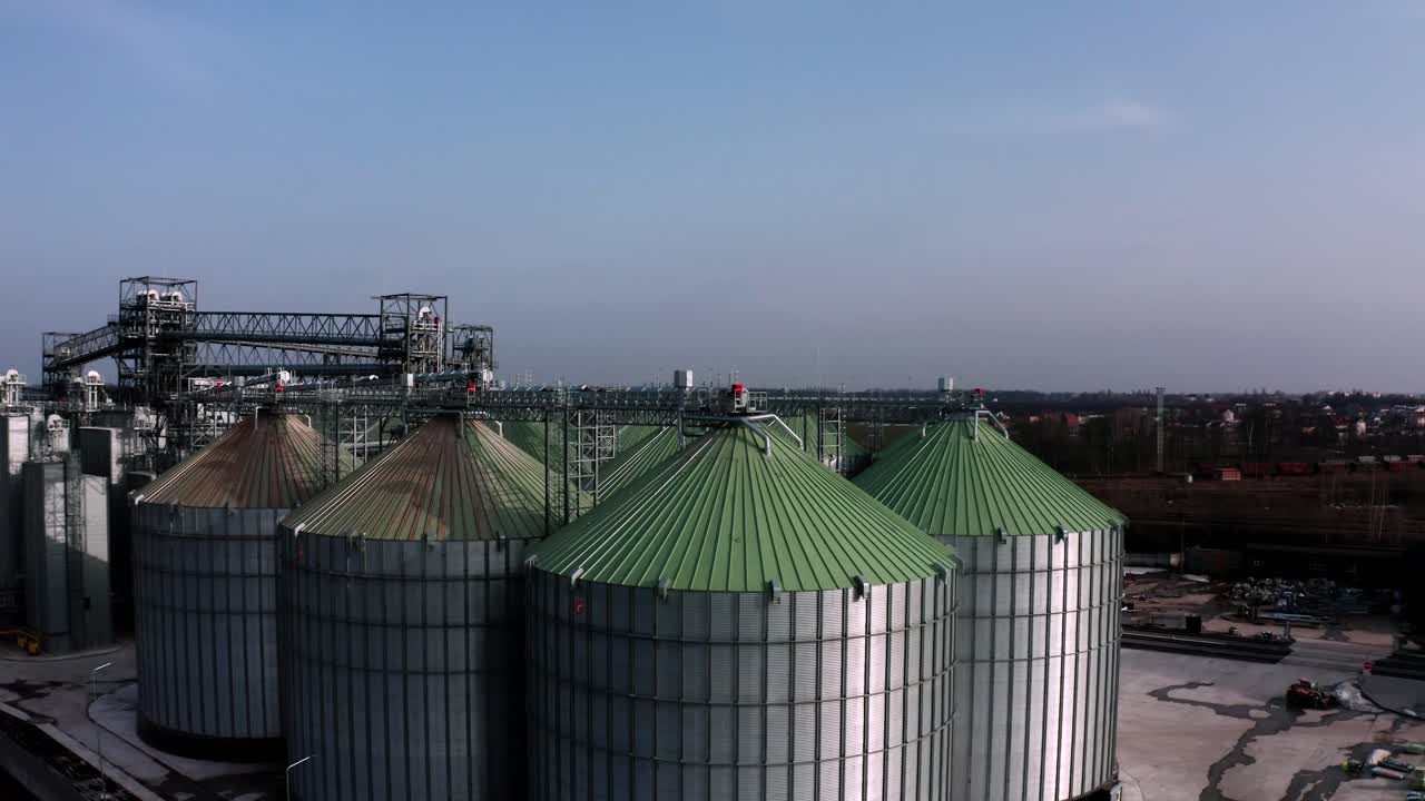 Metal silos on field aerial view. Large containers for storing and processing grains. Silver grain elevators in farmland. Storage tank view from above. Silo with grain.