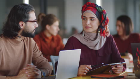 woman in hijab discussing business with male coworker