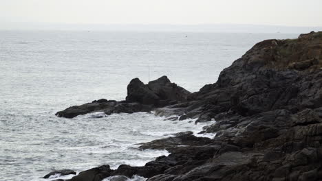 Las-Tranquilas-Olas-Del-Océano-Se-Estrellan-Contra-La-Costa-Rocosa-En-Un-Sombrío-Día-Nublado