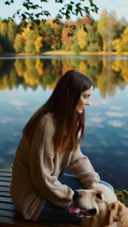 woman and golden retriever enjoying a peaceful autumn day by the lake