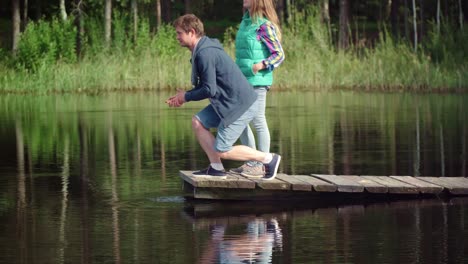 парень касается воды в озере рукой. люди отражаются в воде озера.