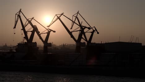 silhouetted port cranes at dusk