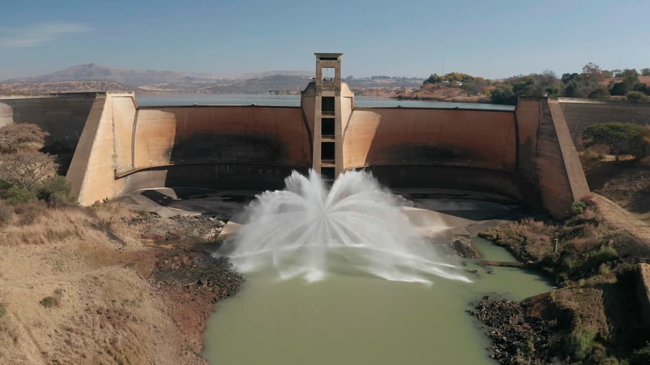 Aerial panoramic view arched dam wall with water discharging