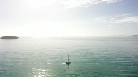 orbiting aerial of catamaran sailboat reveals spectral sun ball on sea