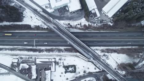 Tren-Pasando-Por-El-Puente-De-La-Autopista,-Invierno,-Droneshot-De-Arriba-Hacia-Abajo,-Aéreo,-Austria